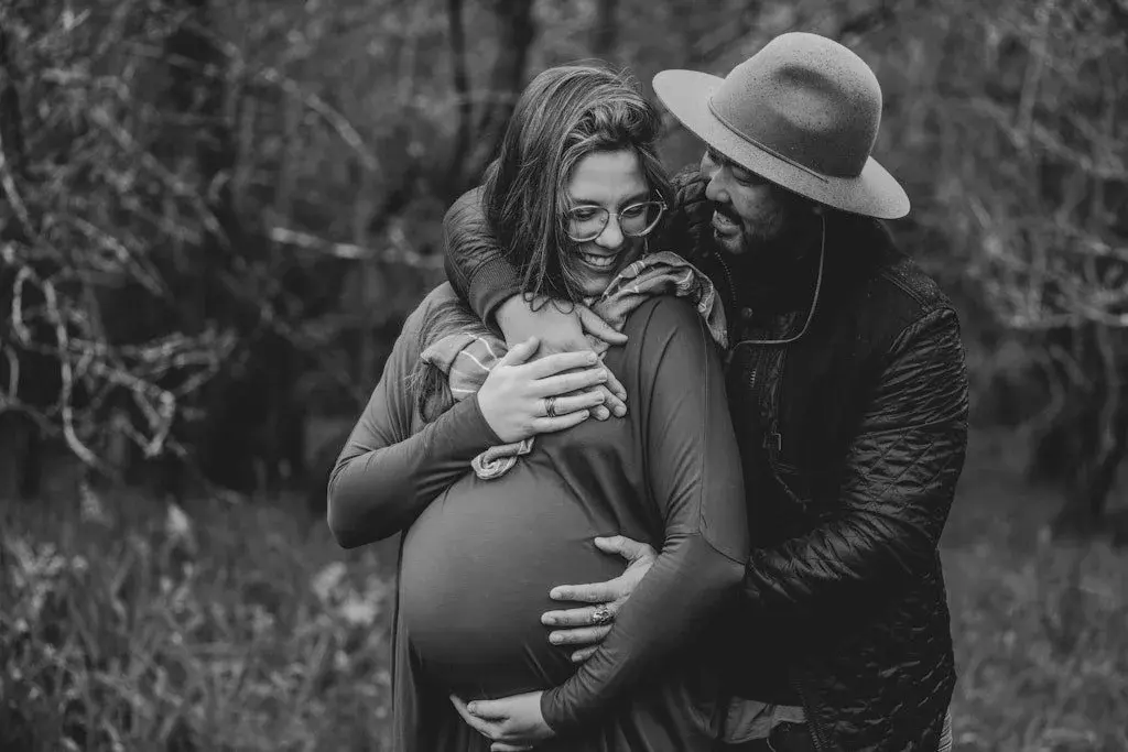 Expecting parents embracing in black and white